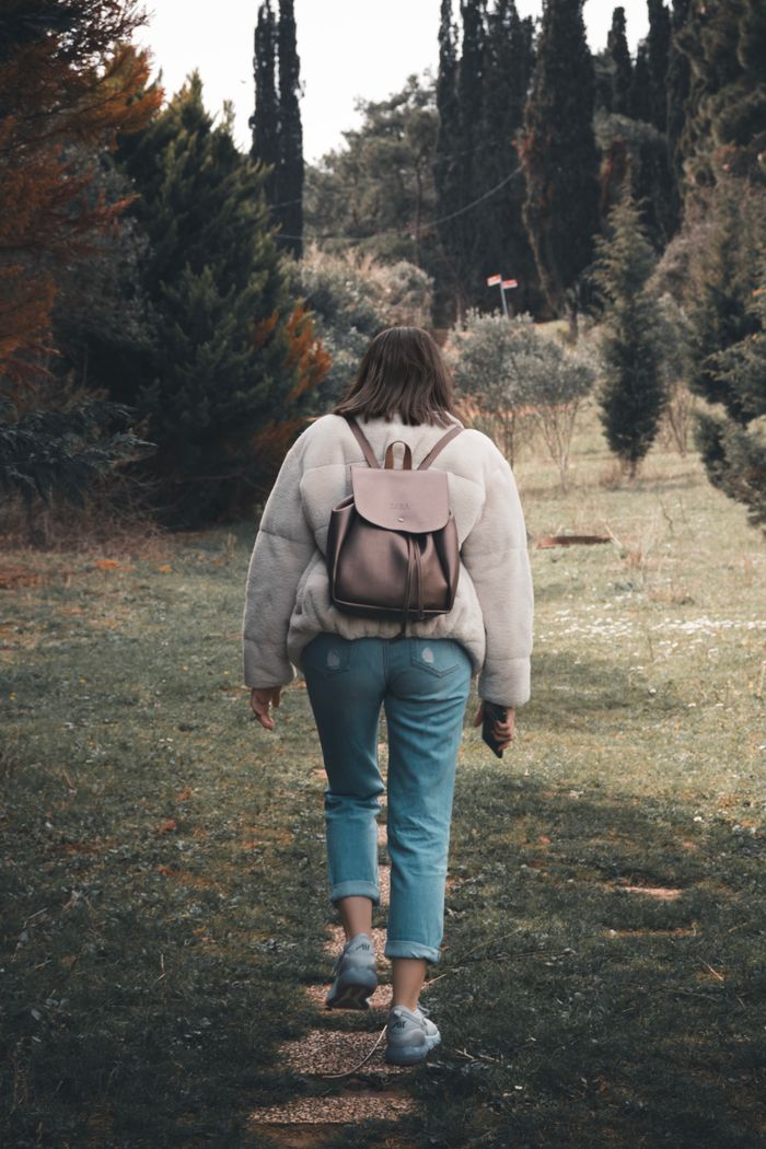 A woman strolls through a scenic park on Heybeliada Island, capturing the essence of autumn outdoor exploration.